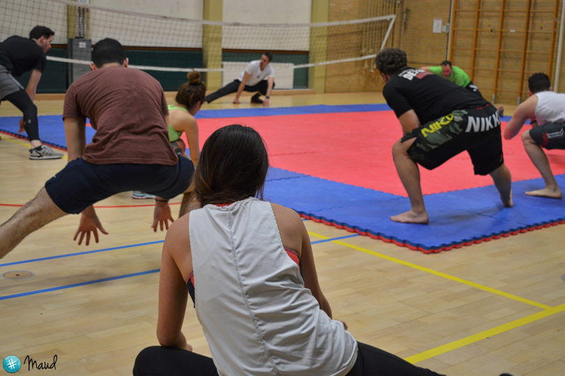 Deelnemers doen een warming-up en mobiliteitsoefeningen tijdens een kickbokstraining in de sportzaal